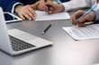 © rogerphoto - Group of business people and lawyer discussing contract papers sitting at the table, closeup. Businessman is signing document after agreement done