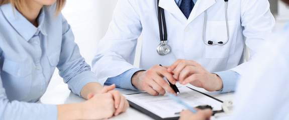 Doctor and  patient  sitting at the desk, close-up of unknown physician at work. Medicine and health care concept