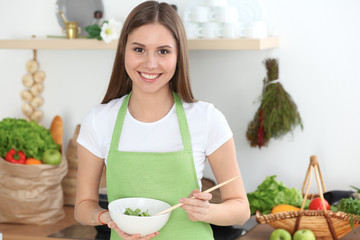 Young happy woman cooking in the kitchen. Healthy meal, lifestyle and culinary concepts. Good morning begins with fresh salad