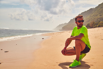 Wall Mural - Sportsman stretching on a exotic tropical beach after jogging / exercising.