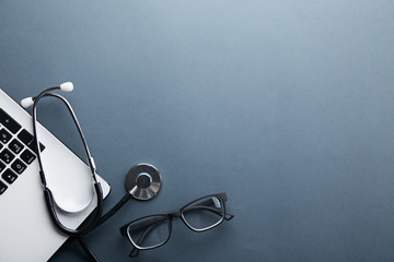 Modern medical technology and sofware advances concept. Doctor's working table with stethoscope acoustic device, laptop computer keyboard close up. Copy space, background, top view, flat lay.