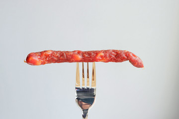 Wall Mural - Hunting sausage on a gray background. Food on fork