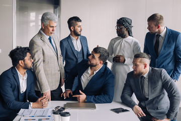 Formal meeting of several multi-ethnic male colleagues gathered in executive s office to discuss new ideas