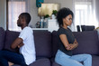 Stubborn black african couple sitting on couch turned back ignoring each other after fight quarrel, offended upset man and woman avoiding talk, family misunderstandings, selfishness in relationships