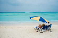 Rest On A Tropical Island. Lie In A Sun Lounger On The Beach Under An Umbrella