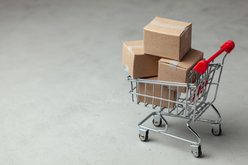 buying goods in the online store. cardboard boxes in the shopping basket on gray background.