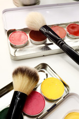 Eye shadows palette and two professional make-up brushes, closeup on white