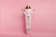 © wayhome.studio  - Relaxed beautiful woman meditates before having sleep, dressed in cotton pyjamas, warm chuni, eyemask, jumps against pink background, enjoys calm domestic atmosphere. Restful girl in nightsuit