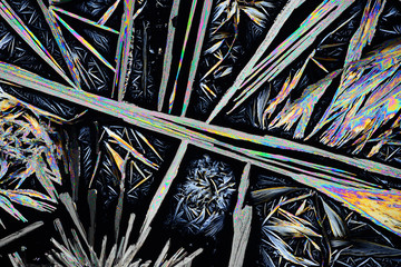 photo through a microscope of crystals grown from a solution of benzoic acid in alcohol. polarized l