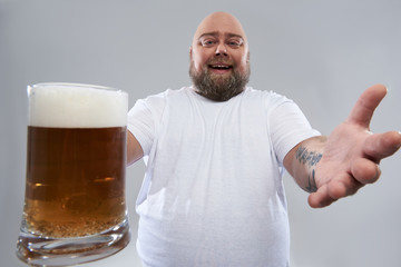 Wall Mural - Close up of big glass of beer in hand of fat funny man