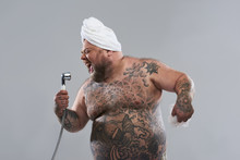 Enthusiastic Tattooed Man Using Shower Head As His Microphone