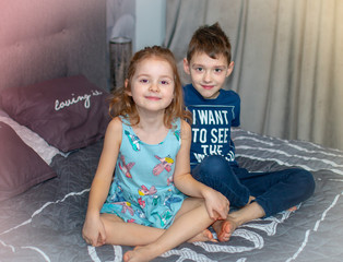 Portrait of two happy smiling kids lin their room. Cheerful brother and sister laughing together.