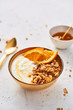 © xMarshall - Bowl of homemade granola with yogurt, honey and fresh orange on white abstract background. Healthy breakfast. Golden utensils. Top view. Copy space for text.