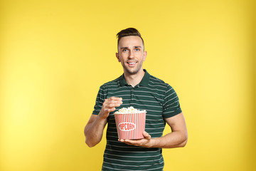 Wall Mural - Man with popcorn during cinema show on color background