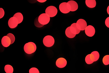 Abstract red bokeh texture on black background. Defocused sparkles.