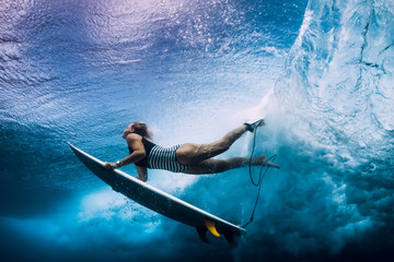 Wall Mural - Surfer woman with surfboard dive under wave