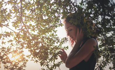 Wall Mural - portrait of a beautiful young woman with dark hair in a frame of branches and green leaves, summer a