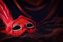 Photo Of Elegant And Delicate Red Venetian Mask Over Dark Velvet And Silk Background.