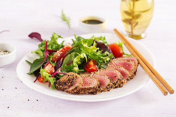 Japanese traditional salad with pieces of medium-rare grilled Ahi tuna and sesame with fresh vegetable salad on a plate. Authentic Japanese food.