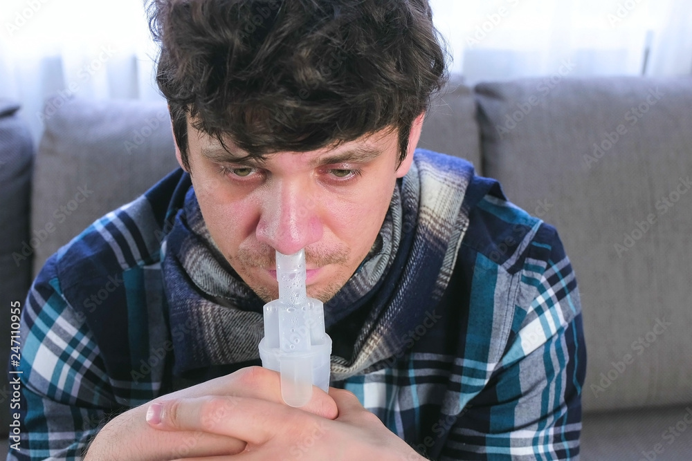 Sick man inhaling through inhaler nozzle for nose. Close-up face, front ...