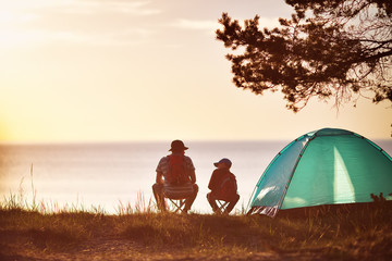 family resting with tent in nature at sunset