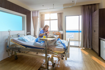 Asian women patients eat breakfast on bed in the hospital's special room in warm sunshine after suffering from severe diarrhea.