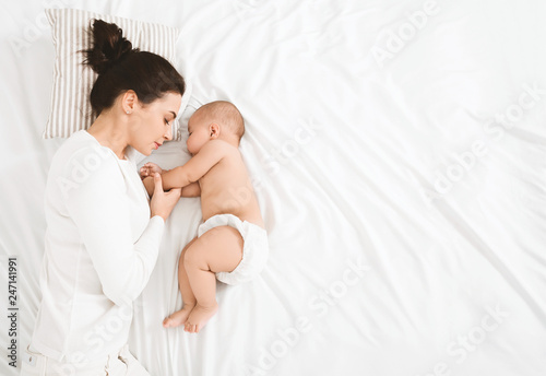 Fotomural Young mom and her cute baby sleeping in bed