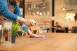 © bignai - Waiter cleaning the table with spray disinfectant on table in restaurant.