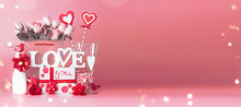 Valentines Day Greeting Objects With Gift Box, Roses Bunch And Hearts In Shopping Bag, Text Love Youu And Ribbons Standing At Red Pink Background With Bokeh, Front View. Declaration Of Love. Banner