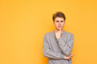 © bodnarphoto - Thoughtful guy stands on a yellow background and looks at the camera. Serious young man is isolated on a yellow background, looking into the camera. Copyspace