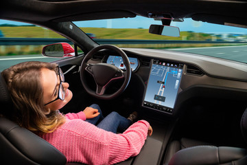 Wall Mural - A woman resting while her car is driven by an autopilot. Self driving vehicle concept