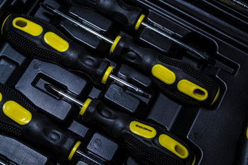 Big tool kit of black and yellow colors for the house in a box. Flat-nose pliers, screw-drivers, stationery knife and nippers. 