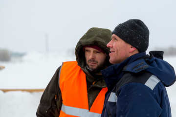 Two workers in overalls at a construction site