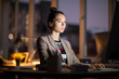 © Seventyfour - Young businesswoman concentrating while reading information on computer screen in dark office