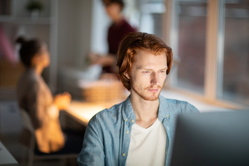 Wall Mural - casual young office worker looking at computer screen while reading online information or watching s