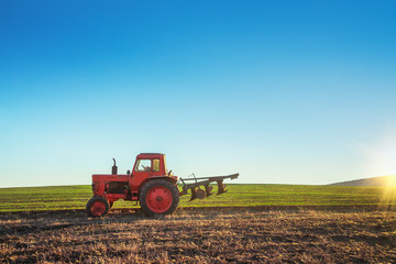 Wall Mural - Tractor cultivating field at spring