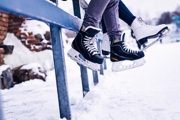 Wall Mural - Couple wearing ice skates sitting on a guardrail. Dating in an ice rink.