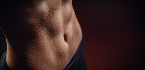 Wall Mural - Closeup of drop of sweat on skin abdomen woman after workout. Dark background