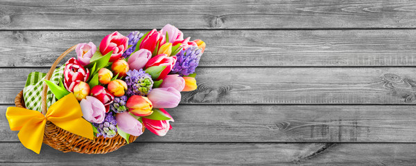 Springtime flowers and basket on wooden background