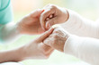 Closeup of hands of young nurse holding hands of an senior lady