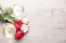 Top Down View Of Two Glasses Of White Wine With Red And Pink Roses On A Reclaimed Wood Background.