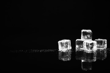 Pile of crystal clear ice cubes on black background. Space for text