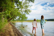 © MNStudio - Two young sisters having fun on a sandy lake beach on warm and sunny summer day. Kids playing by the river.