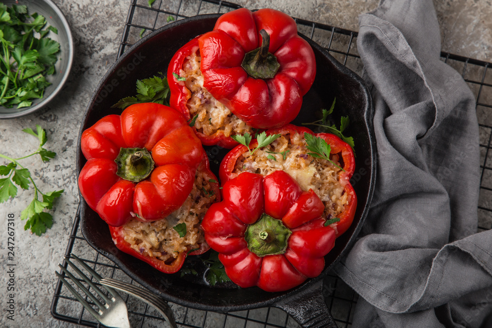 red bell peppers stuffed with meat, rice and vegetables on cast iron pan - obrazy, fototapety, plakaty 