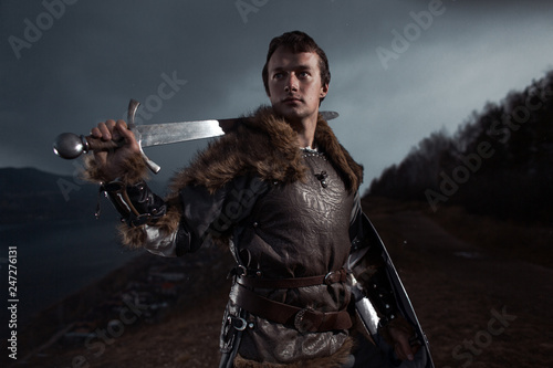 Photographie Medieval knight with sword and spear in ancient armour over Winter Landscapes