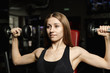 © combo1982 - Active beautiful fitness model girl trains with dumbbells on the bench in the gym.