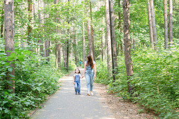 Wall Mural - Family, nature, people concept - Mom and daughter spend time together on a walk in the summer forest