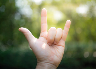 Love with the finger symbol Green tree bokeh as background.soft focus.