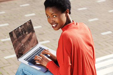 Wall Mural - young woman sitting outside with laptop