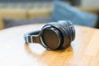 Picture of black wireless headphones on wooden table/ high-quality expensive headphone, music lover, music time, selective focus on headset, top view with copy space/ music and lifestyle concept.